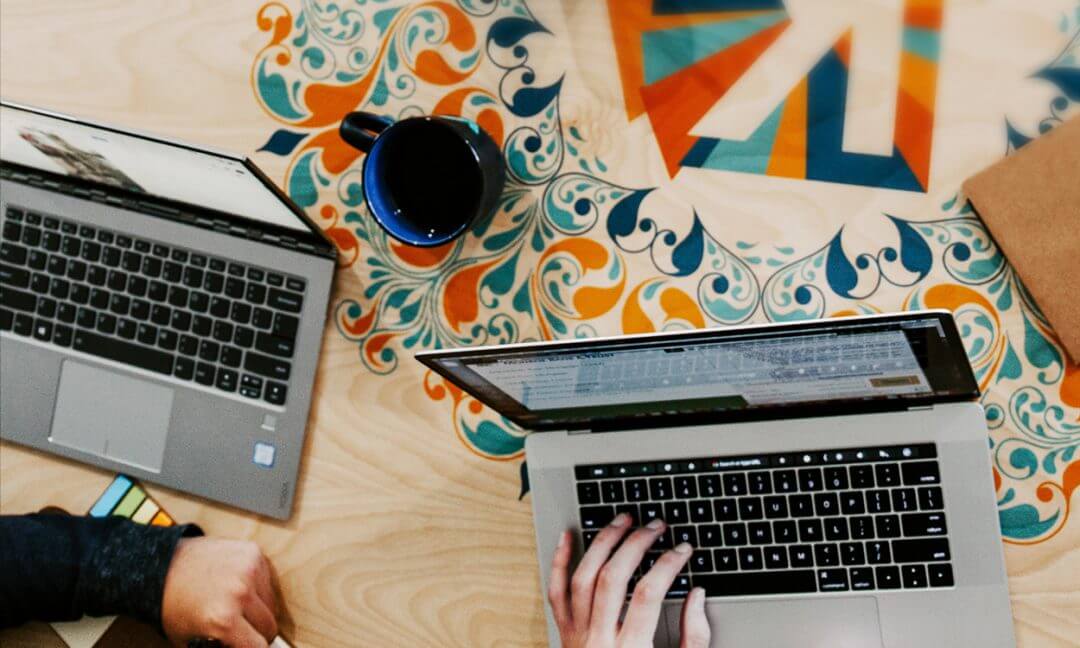 persone al computer che scrivono con quaderno e post it sul tavolo