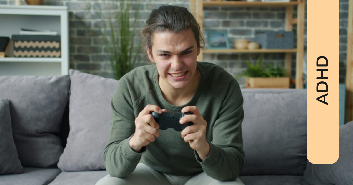 Ragazzo adolescente seduto sul divano di casa con un'espressione di intensa concentrazione, che stringe un controller da videogioco con le mani