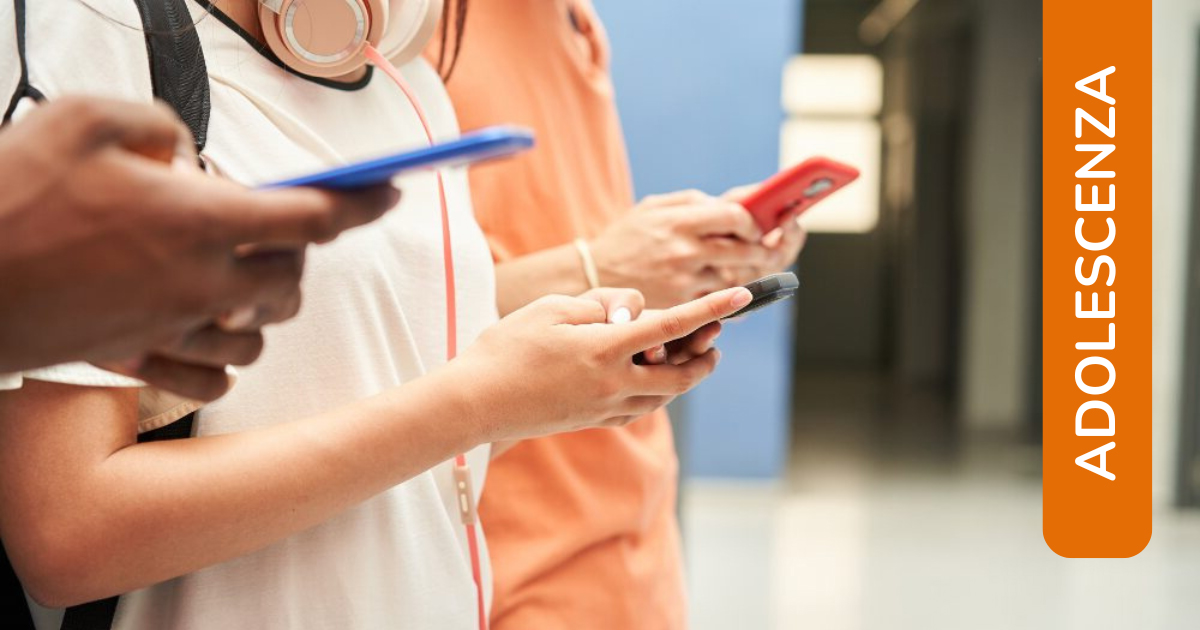 Dettaglio di vari adolescenti affiancati che guardano gli smartphone, in piedi in un corridoio scolastico