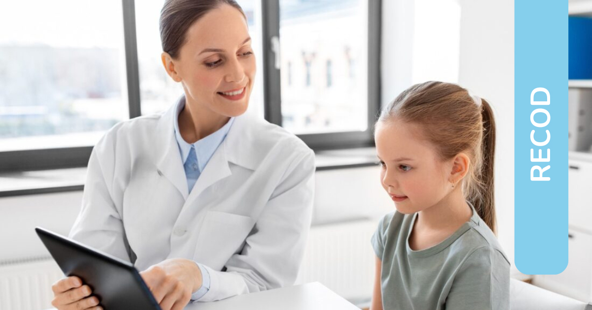 Una specialisti clinica sorridente mostra un tablet ad una bambina curiosa