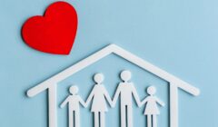 Origami di una famiglia stilizzata all'interno di una casetta con un grande cuore rosso all'esterno