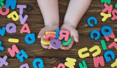 Le mani di un bambino che sorreggono una manciata di lettere di gomma alla rinfusa