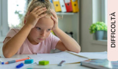 Bambina che si tiene la testa fra le mani sconsolata davanti al quaderno dei compiti da fare