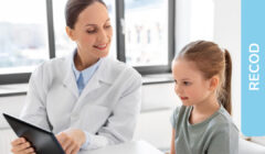 Una specialisti clinica sorridente mostra un tablet ad una bambina curiosa
