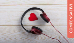 Cuffie audio posate su una superficie di legno chiaro, con un piccolo cuore rosso all'interno dell'archetto