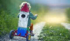 Un bambino va su un triciclo a forza di razzo su una strada di campagna