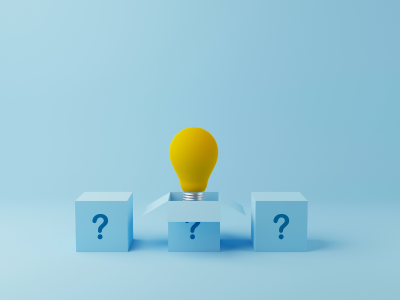 Tre cubi azzurri su sfondo azzurro, ciascuno con un punto interrogativo blu. Dal cubo centrale si apre un coperchio a forma di frecce divergenti, da cui emerge una lampadina gialla, simbolo di un'idea o di una risposta che emerge dall'incertezza.